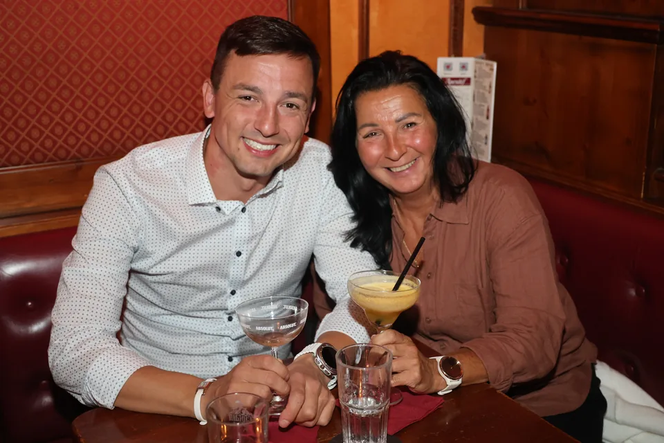 Zwei Gäste mit Cocktails auf einer Sitzbank
